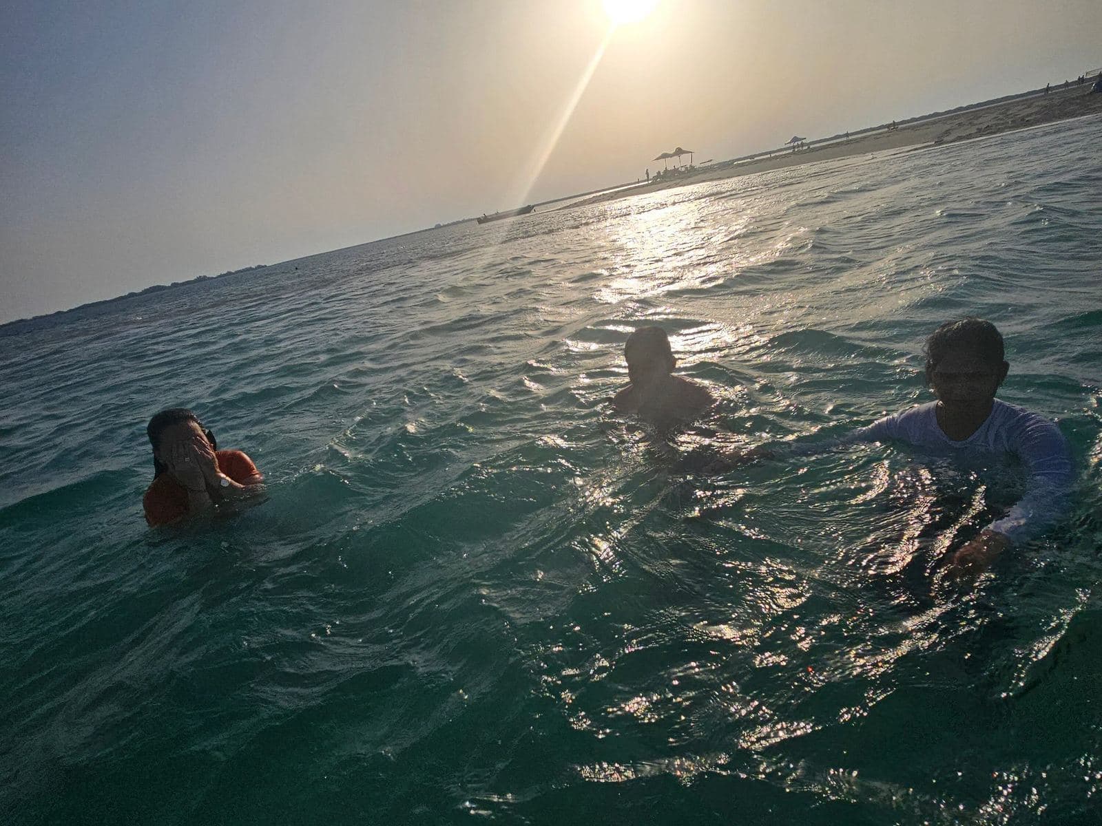 Friends swimming in the sea at sunset near an island